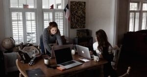 Two young women working collaboratively in a cozy home office setting.